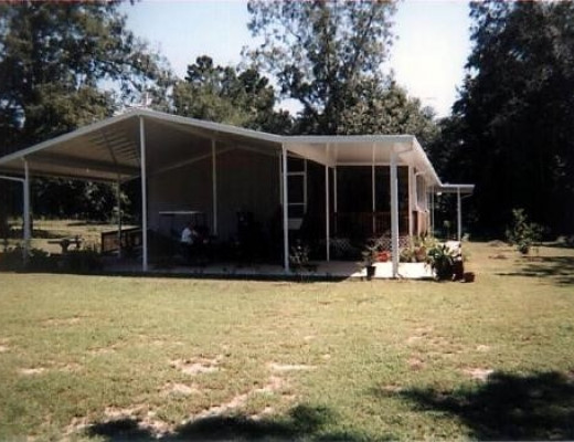 White aluminum carport and patio roof attached to a brick home
